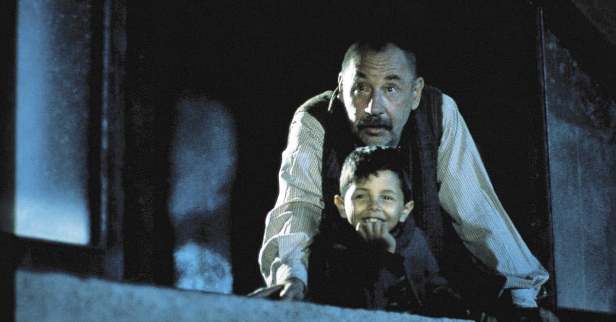 Alfredo and young Toto watching a film projected on a wall in the street, a tender moment from Cinema Paradiso.