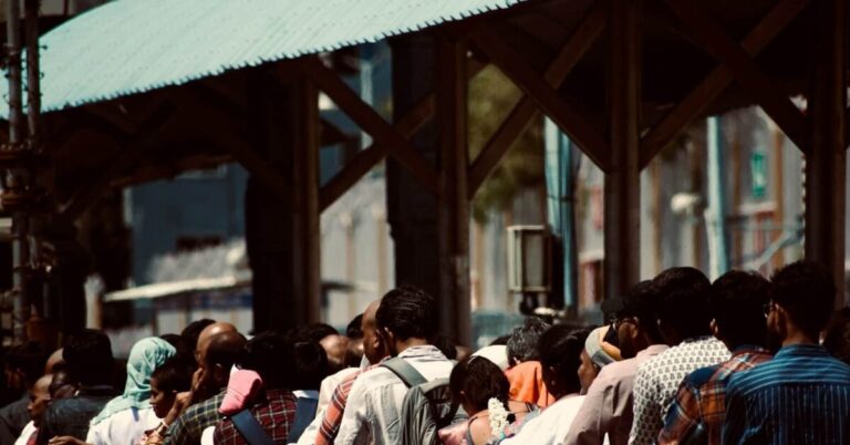 Caste-Based A large crowd waiting behind a metal barrier.